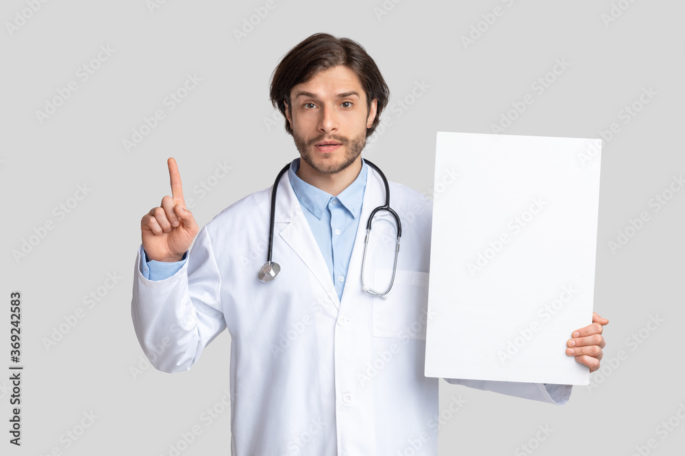 Doctor holding blank warning sign and pointing finger up Doctor holding blank warning sign and pointing finger up