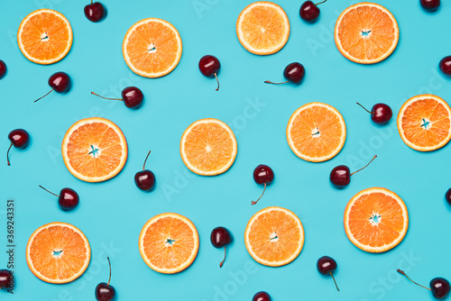 Orange slices and sweet cherries on blue background