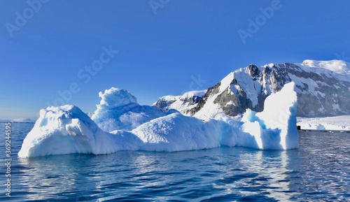 Blue iceberg in antarctic ocean, blue sky, bright sun, melting ice, Antarctica