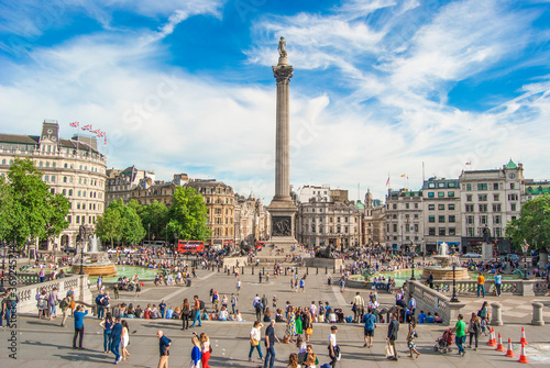 Trafalgar Square with Nelson Pillar and a crowd of people walking around, London, June 2019.
