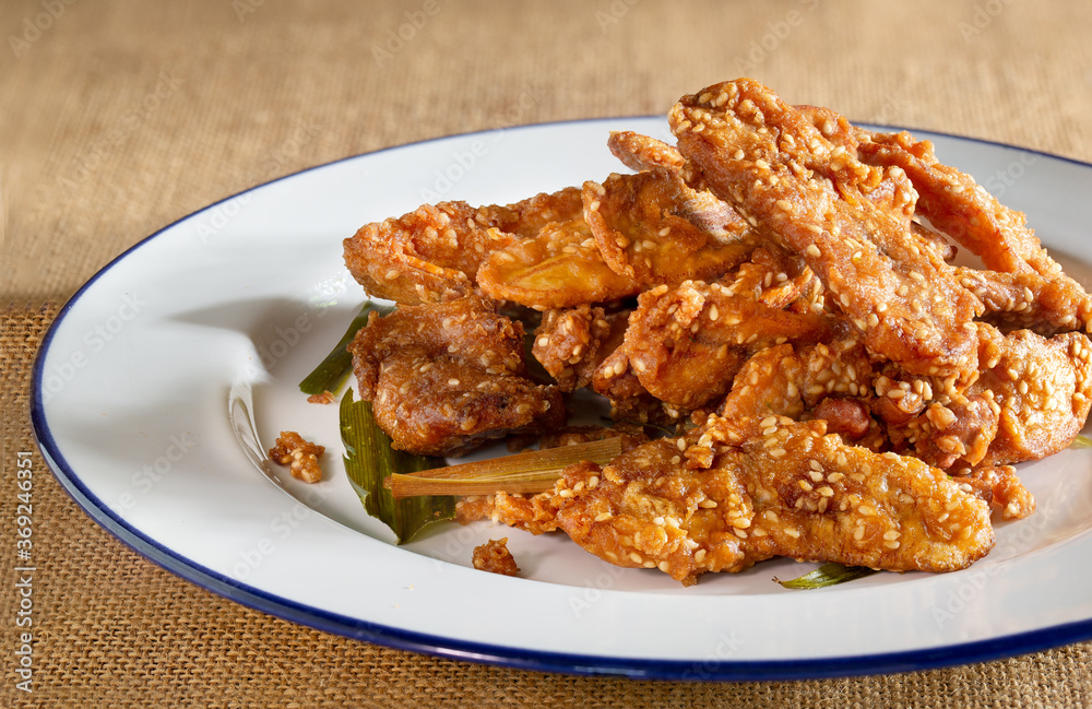 Fried banana mix sesame and pandan leaf for aroma (Thai called Kluay kack) in white dish and on light brown tablecloth Thai snack Fried banana mix sesame and pandan leaf for aroma (Thai called Kluay kack) in white dish and on light brown tablecloth Thai snack