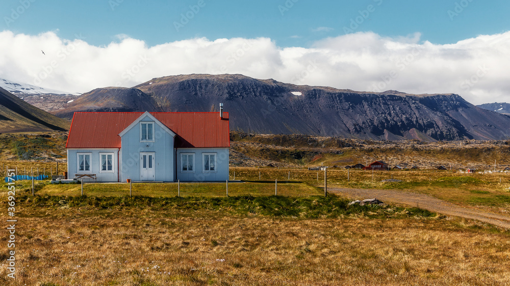 Impressive summer view at sunny day of Iceland. Wonderful nature of Iceland. Typical Icelandic landscape during sunset with houses against mountains in Arnarstapi village of at Snafellsnes Peninsula,