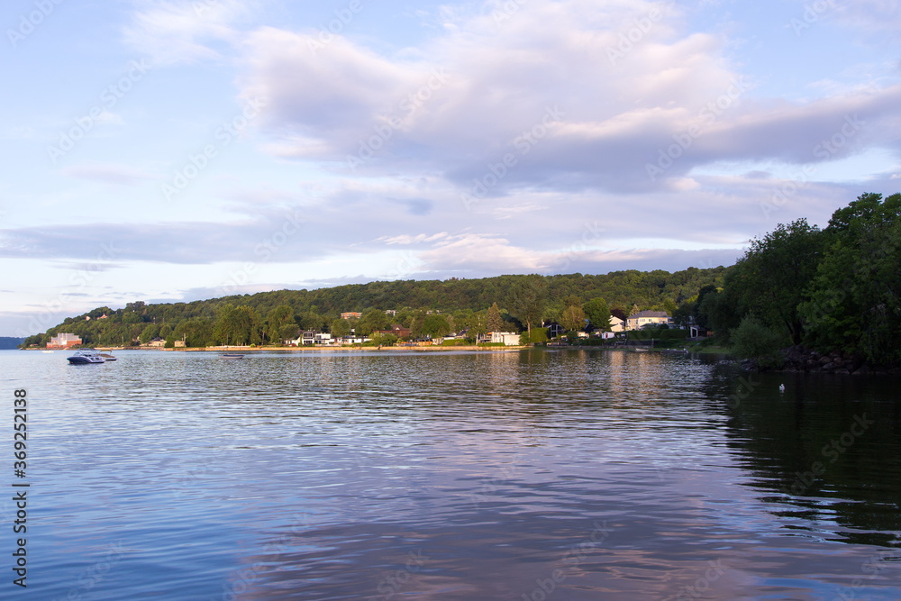 Early morning summer view of the Cap-Rouge bay with small boats moored in the St. Lawrence River and a lone snow goose floating in the water Early morning summer view of the Cap-Rouge bay with small boats moored in the St. Lawrence River and a lone snow goose floating in the water