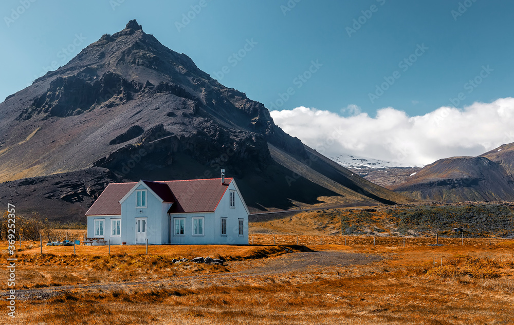 Impressive summer view at sunny day of Iceland. Wonderful nature of Iceland. Typical Icelandic landscape during sunset with houses against mountains in Arnarstapi village of at Snafellsnes Peninsula