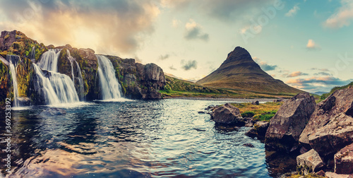 Amazing mountain landscape with colorful vivid sunset on the cloudy sky over the famous Kirkjufellsfoss Waterfall and Kirkjufell mountain. Iceland. popular location for landscape photographers.