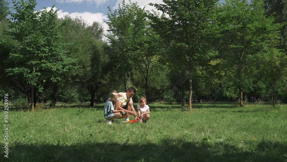 Family day, father with kids sets up a kite, outdoor activities with children. Family day, father with kids sets up a kite, outdoor activities with children.
