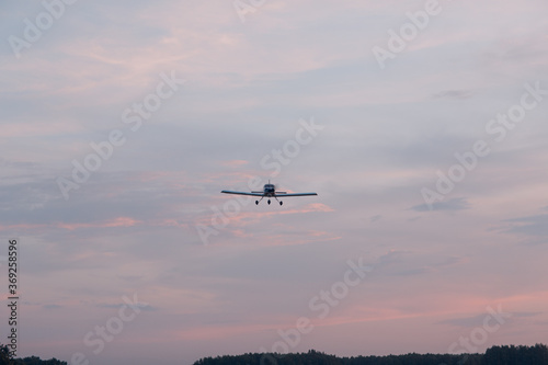 Small single engine airplane flying against sunset sky.