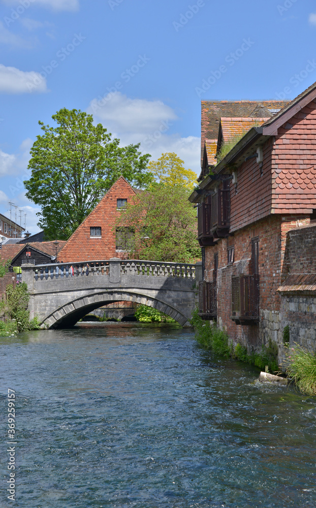 River Itchen in Winchester flowing alongside medieval buildings with the City Bridge in the background.