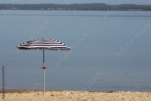 Blau weisser Sonnenschirm vor einem ruhigen See
