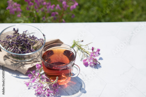 Chamaenerion angustifolium tea (cypress, big willow, pink willow) with dry and fresh flowers for decoration in glass cups on a light background. Concept of herbal medicine. Horizontal orientation