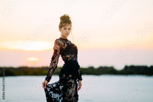 Woman stands and poses in desert at sunset. photo