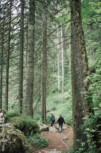 Group of tourists hiking on a mountain woods trail. Fun outdoor activities in the summer. Active and healthy lifestyle. Enjoying wildlife nature.
