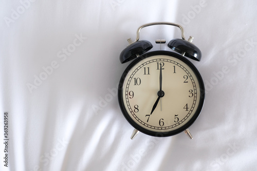 Alarm clock on white bed with copy space for you design..