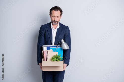 Photo of unhappy displeased stressed worker mature guy lost job jobless hopeless financial crisis hold carton box belongings fired quit tired walk home wear suit isolated grey background