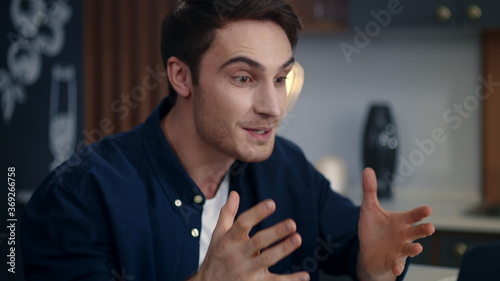 Excited businessman celebrating success on video call at remote workplace.