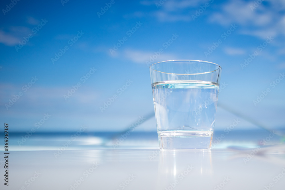 Glass of water standing near swimming pool in hot summer Glass of water standing near swimming pool in hot summer
