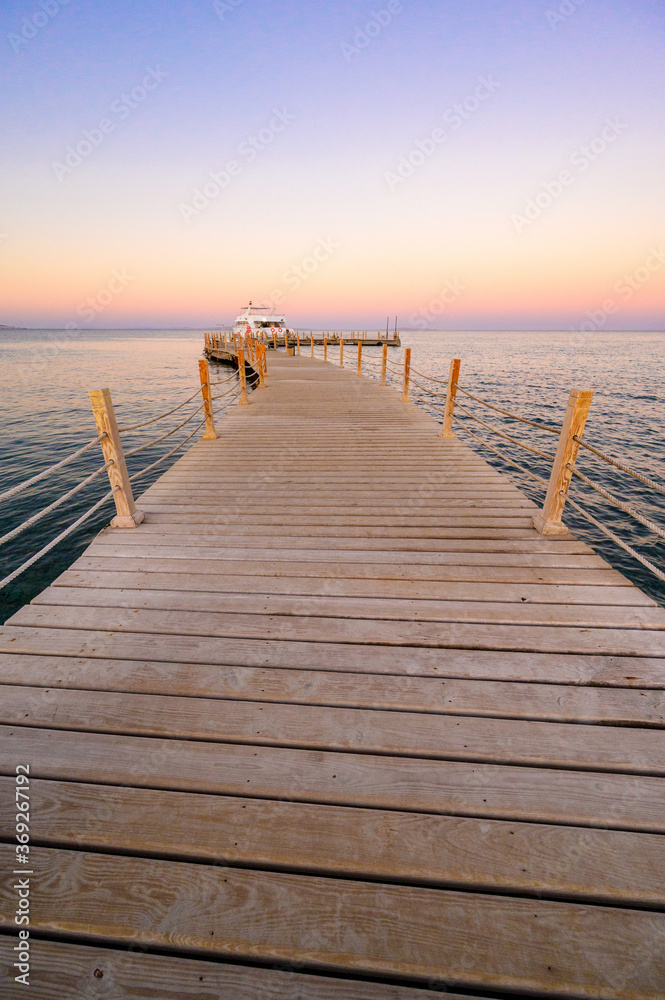 Wooden Pier on Red Sea in Hurghada at sunset and luxury yacht, View of the promenade boardwalk - Egypt, Africa
