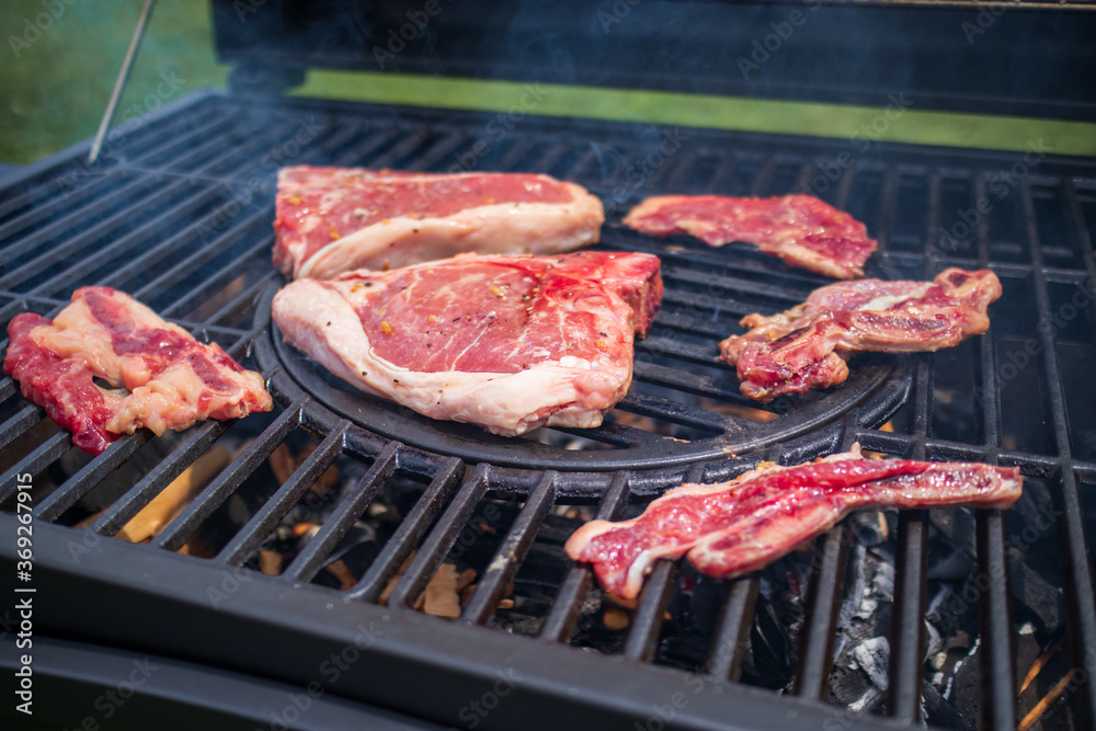 Home barbecue with charcoal in the backyard grilling steaks and other meats for carnivore diet. Home barbecue with charcoal in the backyard grilling steaks and other meats for carnivore diet.