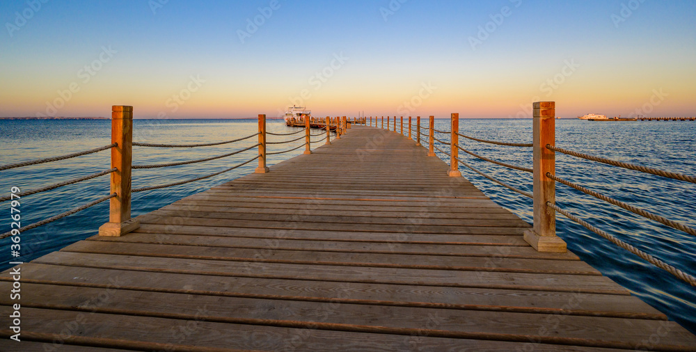 Fototapeta premium Wooden Pier on Red Sea in Hurghada at sunset and luxury yacht, View of the promenade boardwalk - Egypt, Africa