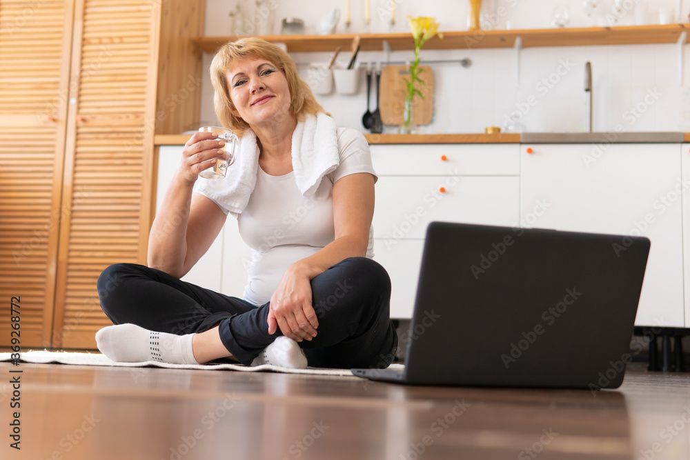 A middle-aged woman does fitness in a bright room. A middle-aged woman does fitness in a bright room.