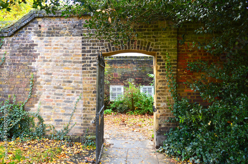 open metal gate with an old brick wall around it
