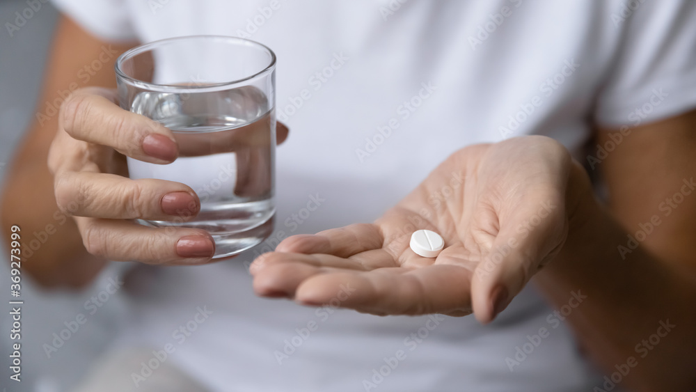 Close up mature woman hands hold pill and glass of natural clean water. Older generation female take analgetic painkiller drug. Painful old age, caring for health of senior citizen, daily meds concept Close up mature woman hands hold pill and glass of natural clean water. Older generation female take analgetic painkiller drug. Painful old age, caring for health of senior citizen, daily meds concept