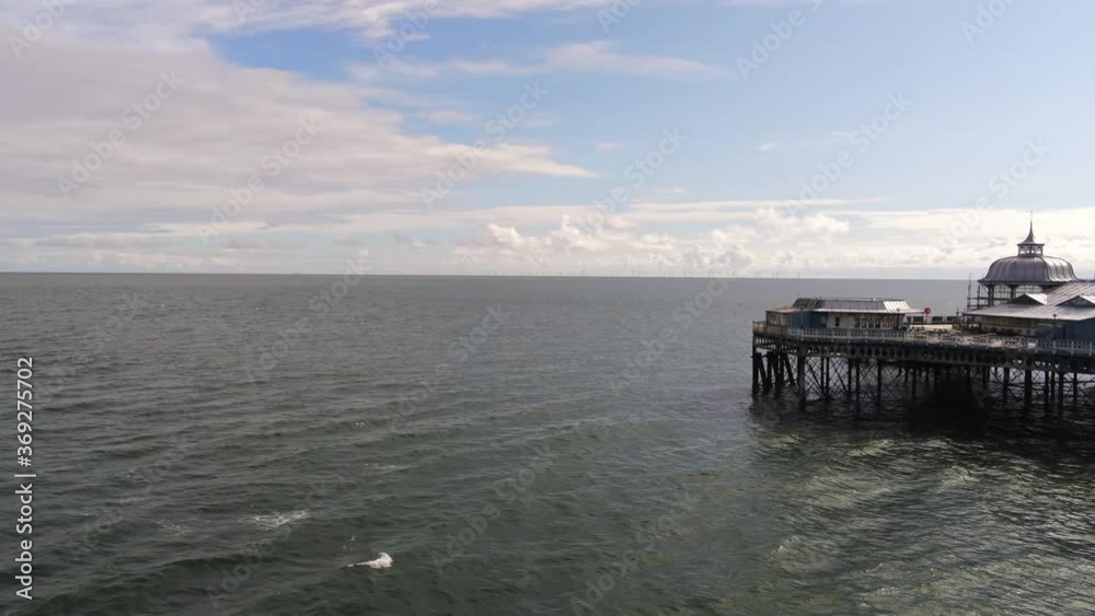 Aerial view historic Llandudno pier landmark tourist seaside promenade landmark pan right reveal Aerial view historic Llandudno pier landmark tourist seaside promenade landmark pan right reveal