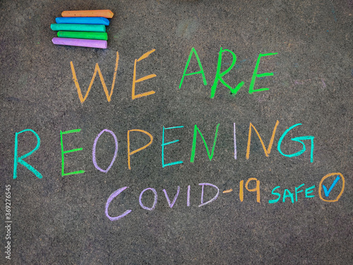 The inscription text on the grey board "WE ARE REOPENING". Using color chalk pieces.