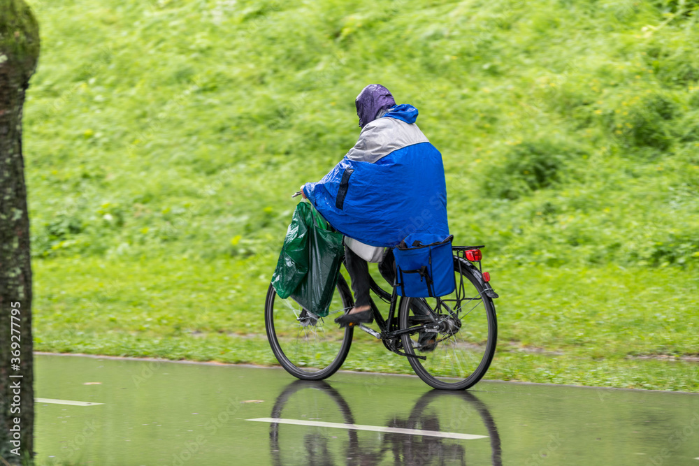 Obraz premium Radfahrer mit Regenpelarine am Radweg
