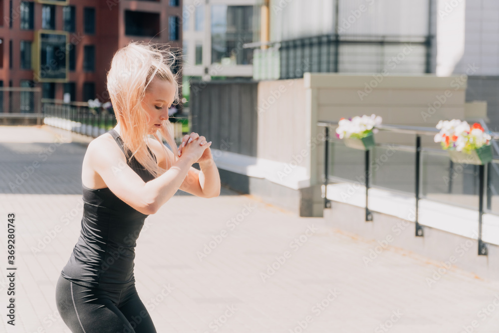 Fototapeta premium A girl in sportswear outdoors does squats, exercise of the gluteal muscles for weight loss