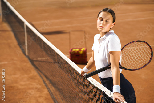Beautiful girl with a racket posing on the tennis court © Andrii 