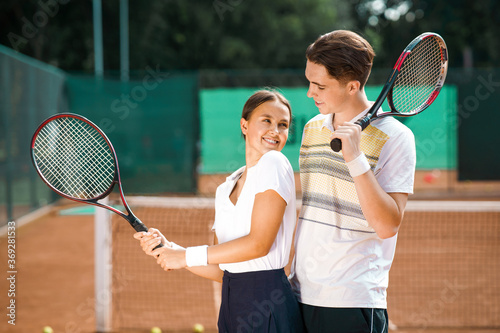 Young couple standing on the tennis court after the game and looking at each other