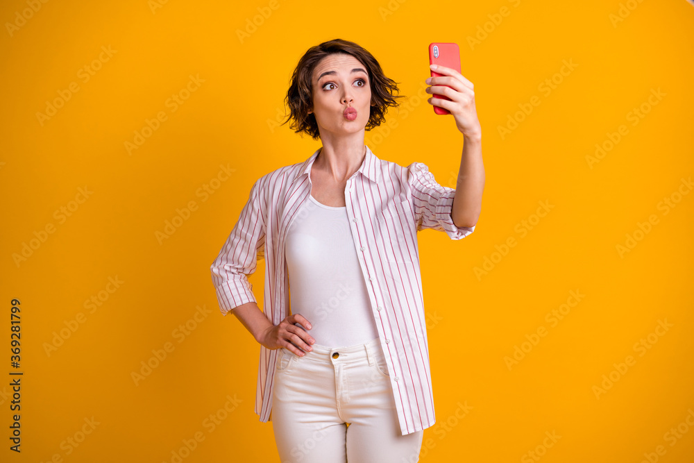 Photo of romantic dreamy girl make selfie on her smartphone send air kiss to her blog followers wear white trousers isolated over bright shine color background Photo of romantic dreamy girl make selfie on her smartphone send air kiss to her blog followers wear white trousers isolated over bright shine color background