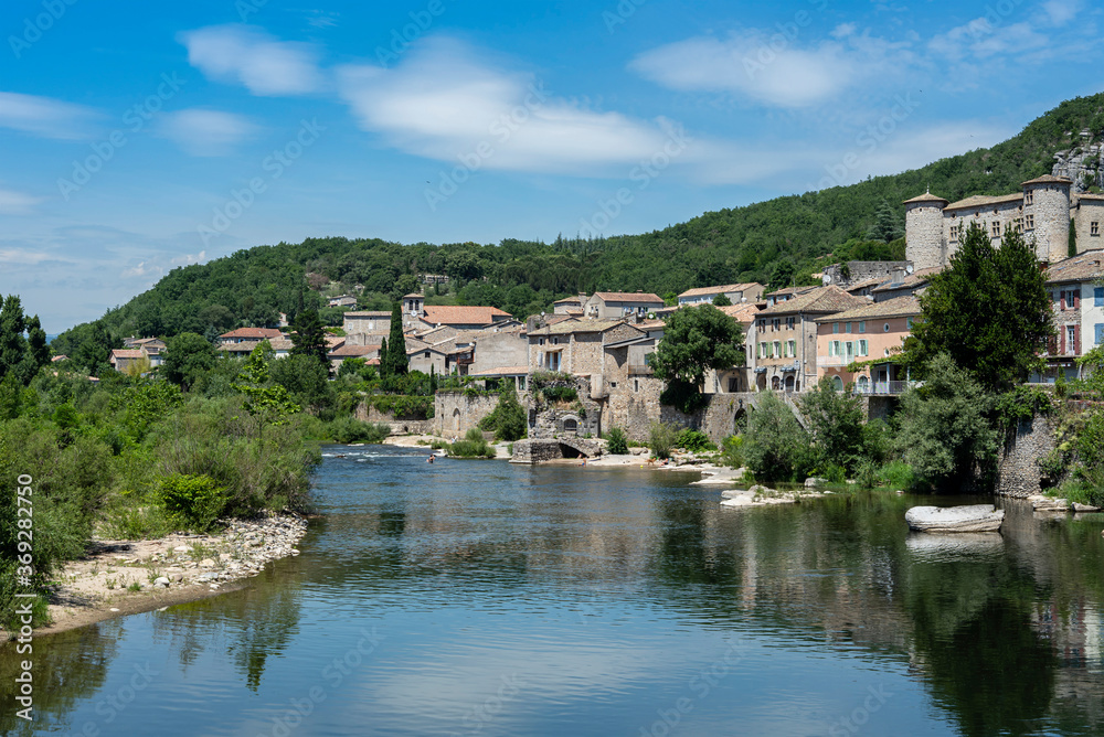 View of the Ardeche river banks with clouds reflecting in the water at french medieval Vogue village.