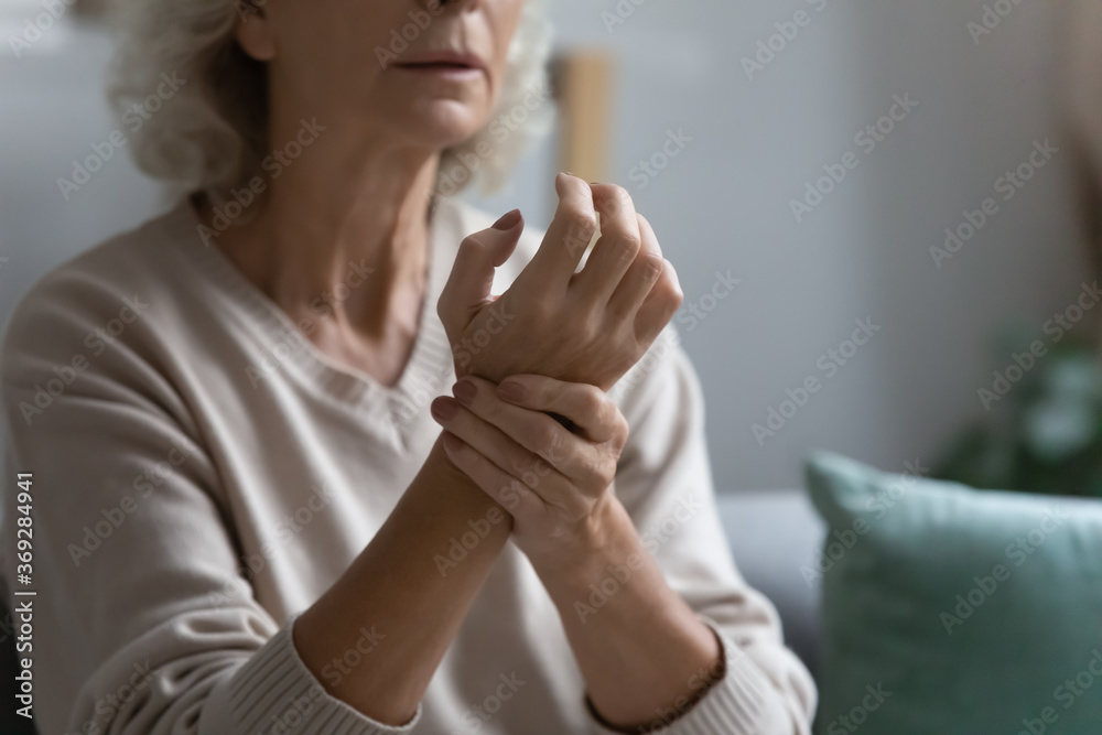 Elderly woman sit on couch alone at home feels dizziness unhealthy, touch wrist check pulse counts heart rate close up view. Senior healthcare, medicine and treatment, heart attack prevention concept Elderly woman sit on couch alone at home feels dizziness unhealthy, touch wrist check pulse counts heart rate close up view. Senior healthcare, medicine and treatment, heart attack prevention concept