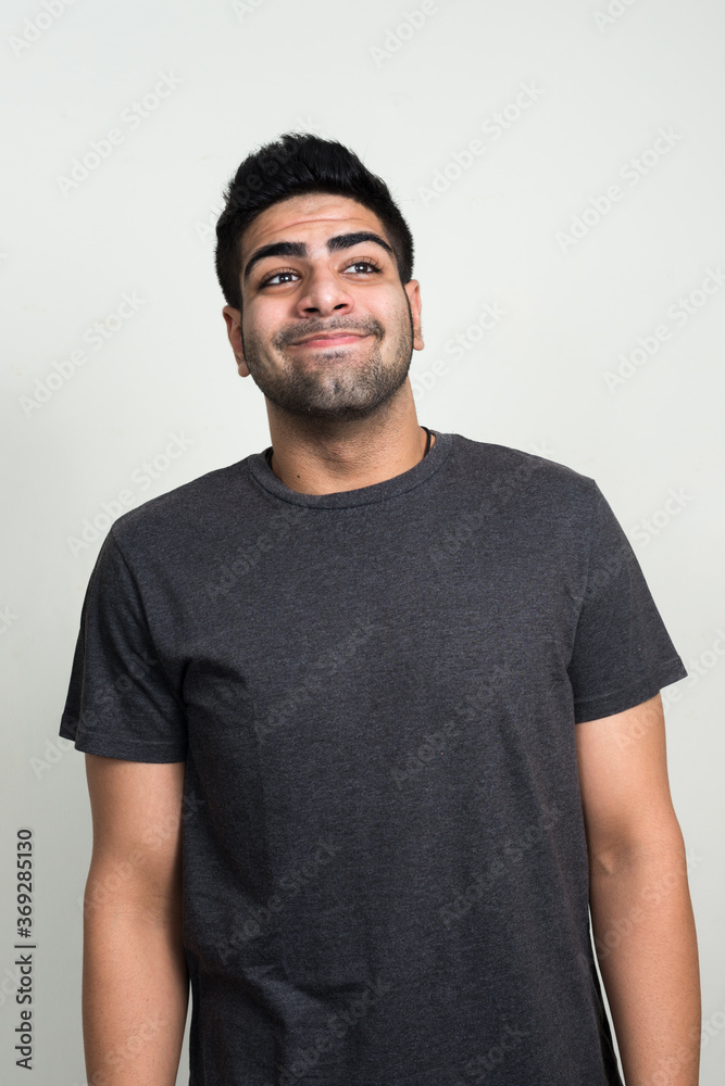 Fototapeta premium Happy young handsome bearded Indian man thinking