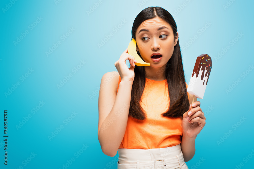 beautiful asian girl holding banana and paper ice scream on blue beautiful asian girl holding banana and paper ice scream on blue
