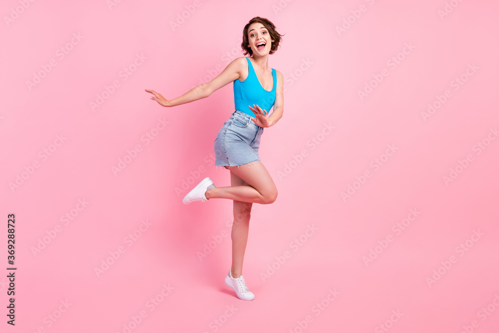 Full body size photo of pretty lovely young girl careless dancing smiling have fun open mouth weekend wear denim mini skirt blue singlet white sneakers isolated pink color background Full body size photo of pretty lovely young girl careless dancing smiling have fun open mouth weekend wear denim mini skirt blue singlet white sneakers isolated pink color background