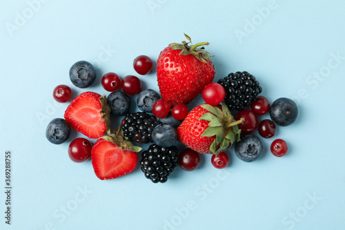 Mix of fresh berries on blue background, top view