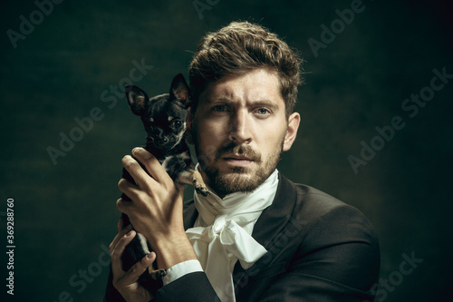 Me and youth. Young man in suit as Dorian Gray isolated on dark green background. Retro style, comparison of eras concept. Beautiful male model like classic literature character, old-fashioned. photo