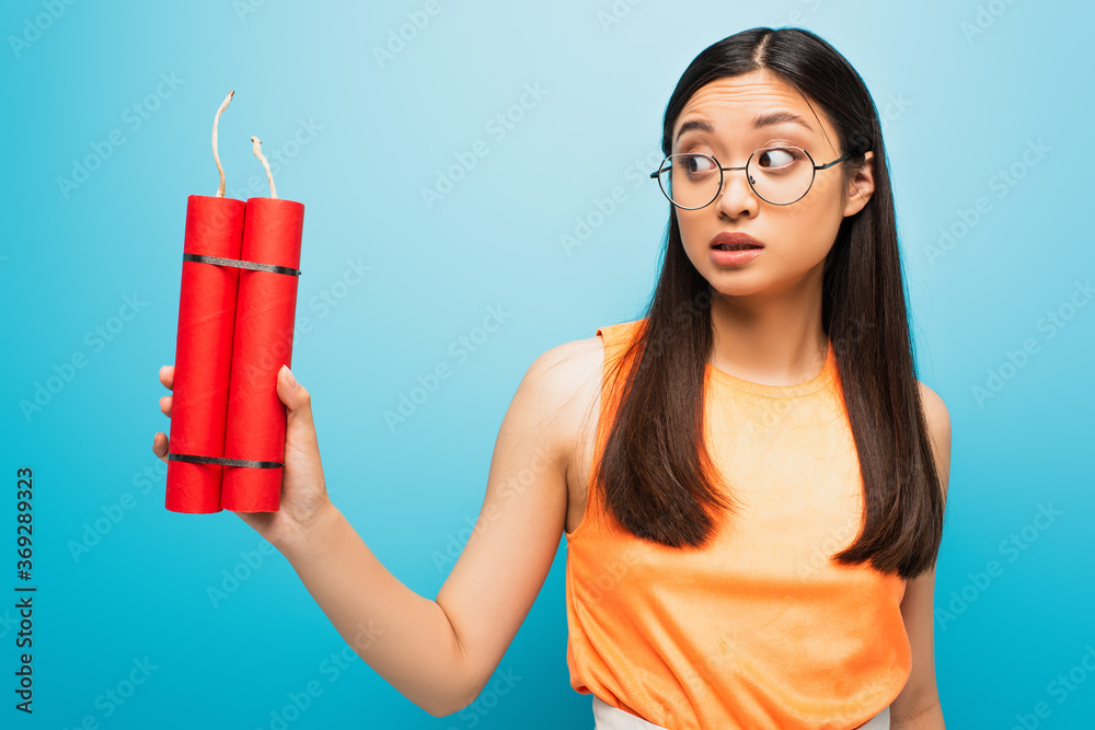 emotional asian girl in glasses holding dynamite sticks on blue emotional asian girl in glasses holding dynamite sticks on blue