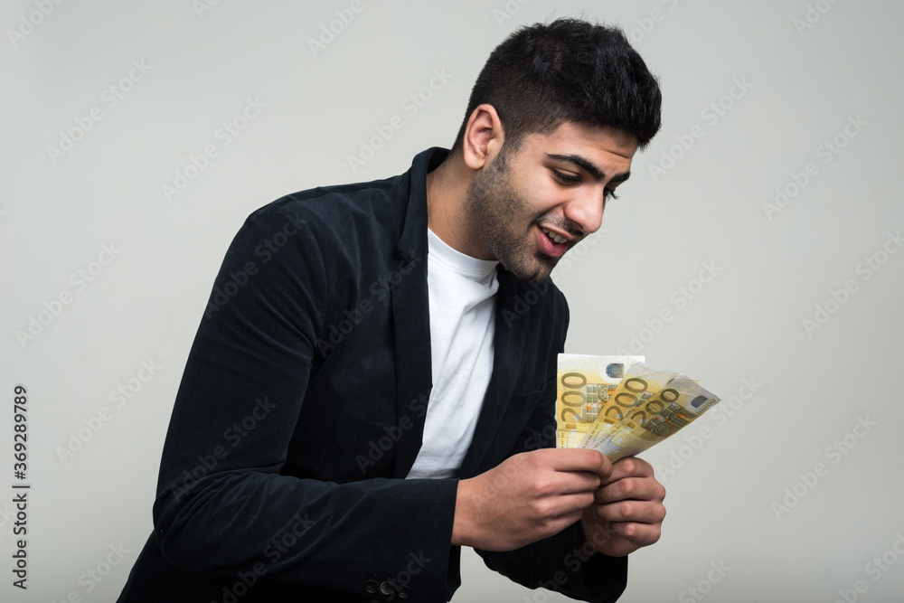 Happy young handsome bearded Indian businessman with money Happy young handsome bearded Indian businessman with money