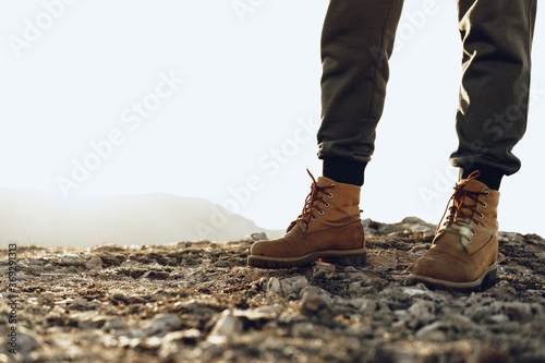 Legs of a backpacker in hiking boots standing on the top of the mountain photo