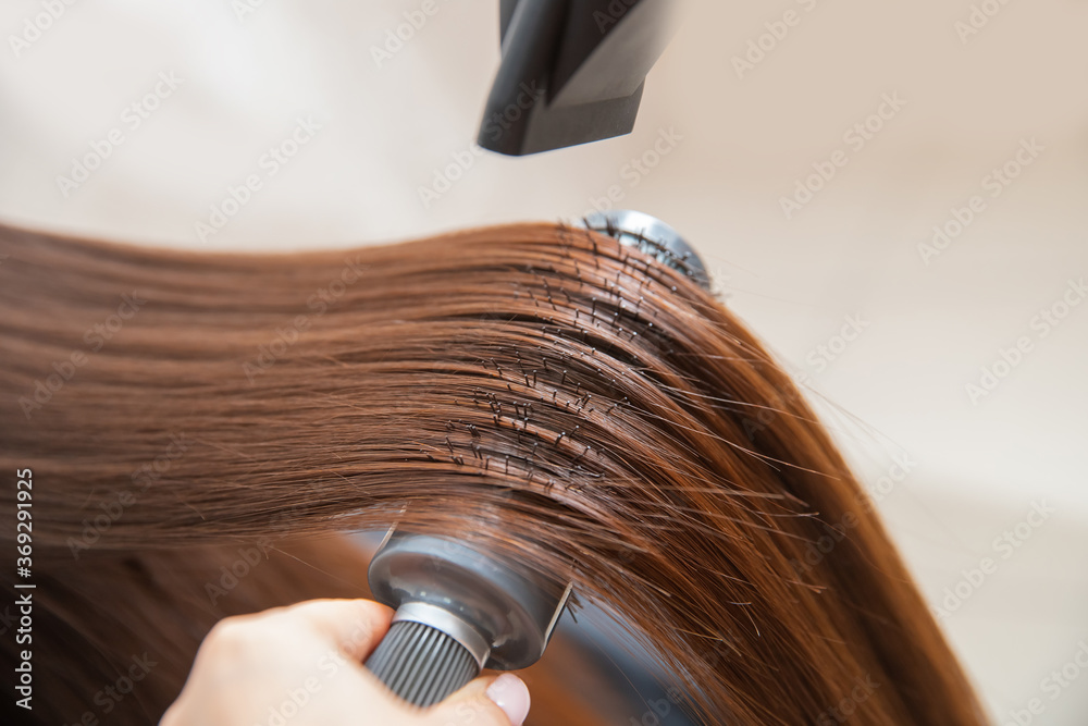 Naklejka premium Master hairdresser blow dry client of young woman in spa beauty salon