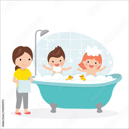 Mother holding towels and happy children sits in bathtub with soap bubbles.