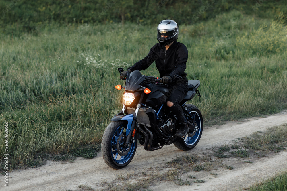 Photo of biker driving motorcycle in sunset on the country road. Photo of biker driving motorcycle in sunset on the country road.