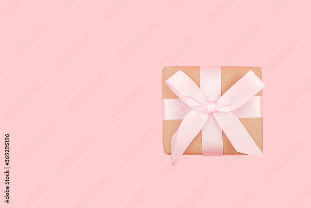 Greeting card with copy space. Gift box with a bow on a pink background. 