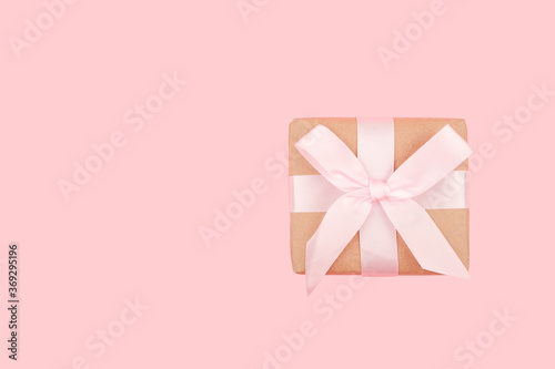 Greeting card with copy space. Gift box with a bow on a pink background.  © Anna