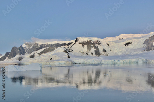 Antarctica, glacier and mountain reflection in ice water, calm evening sunset