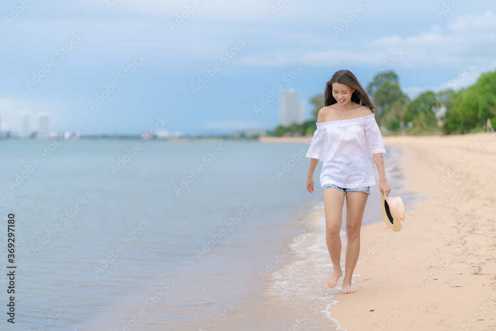 Happy traveler asian woman in white casual wear holding a hat while enjoying a walk on the sea beach at Pattaya, Thailand. Summer travel and vacation concept, Happy traveler asian woman in white casual wear holding a hat while enjoying a walk on the sea beach at Pattaya, Thailand. Summer travel and vacation concept,